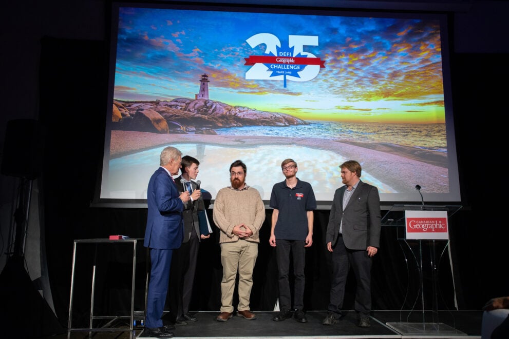 A group of men stand together on a stage talking